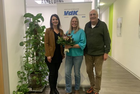 von links: Anna Ortmann, Anika Haid, Dirk Brosge 3 Personen. In der Mitte die geehrte Frau mit Blumenstrauß