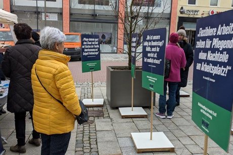 Abgebildet sind Passanten inmitten der Schilder der stillen Demo