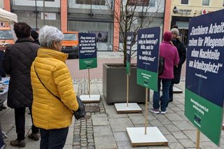 Abgebildet sind Passanten inmitten der Schilder der stillen Demo