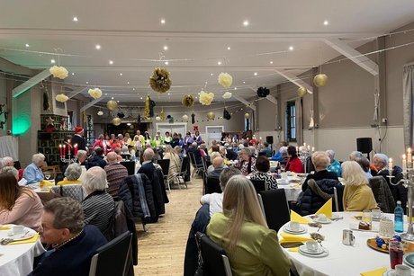 Saal mit G&auml;sten an runden Tischen