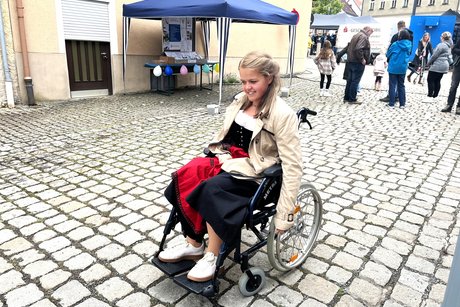 Eine junge Frau testet den Rollstuhl auf Kopfsteinpflaster Eine junge Frau testet den Rollstuhl auf Kopfsteinpflaster