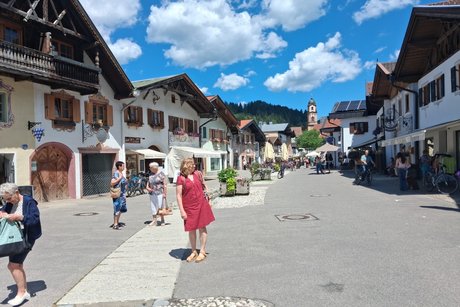 Blick in die Fu&szlig;g&auml;ngerzone am Obermarkt in Mittenwald mit dem historischem Ortskern und im Hintergrund der Kirchturm der Kirche St. Peter und Paul.