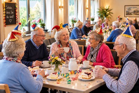 vier Senioren sitzen in einem Caf&eacute; und sind bei Kaffee und Kuchen im Gespr&auml;ch