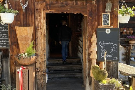 Die Unterhofalm Eingang der Unterhofalm in Holzbauweise mit Blumen geschmückt