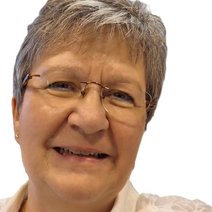 Eine l&auml;chelnde Frau mittleren Alters mit Brille und kurzen graumelierten Haaren