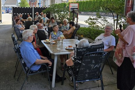Viele Personen sitzen an Tischen im Biergarten