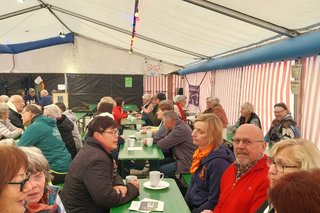 Gäste sitzen im Bierzelt und unterhalten sich