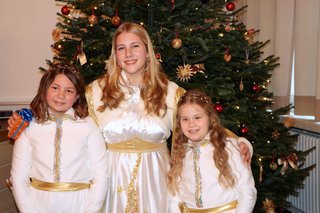 Das Treuchtlinger Christkind steht mit seinen beiden Engeln vor dem Weihnachtsbaum