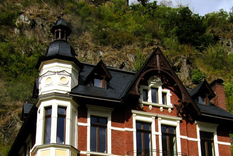 Eine alte Villa mit der Burgruine Are im Hintergrund