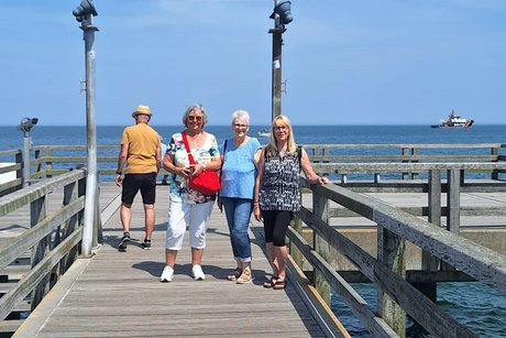 Abgebildet sind Reiseteilnehmer auf einem Steg bei blauem Himmel