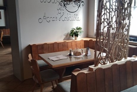 Gasthaus "Anna's Hofstübla" vorderer Gastraum Blick in den vorderen Gastraum, an der Wand "Willkommen in Anna' Hofstübla, U-Förmige Eckbank mit Gästetisch, Raumteiler mit Pflanzen, Fenster zur Hauptstraße