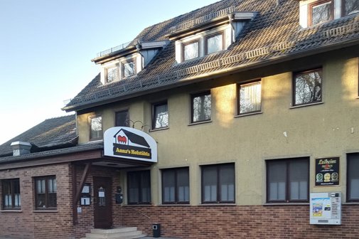 Stra&szlig;enansicht des Haupteingeng zum Gasthaus &bdquo;Anna&rsquo;s Hofst&uuml;bla mit Werbetafel und Tabackautomat