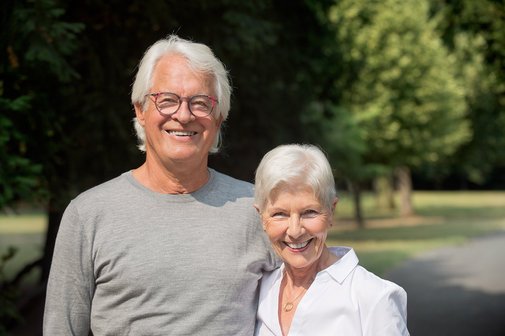 Ein &auml;lterer Mann und eine &auml;ltere Frau stehen nebeneinander, sie l&auml;cheln in die Kamera. 