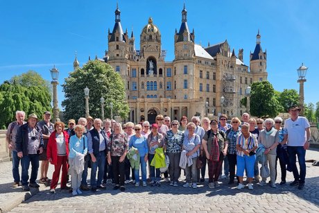 Abgebildet ist die Reisegruppe des VdK-Kreisverbandes Hof vor dem von einer goldenen Kuppel und zahlreichen Türmen gekrönten Schweriner Schloss