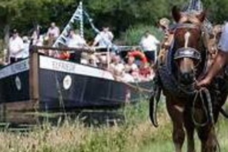 Treideln kanallandschaft mit einen schleppkahn gezogen von einen Pferd. Auf dem Boot sind Leute in frölicher Stimmung zu sehen.