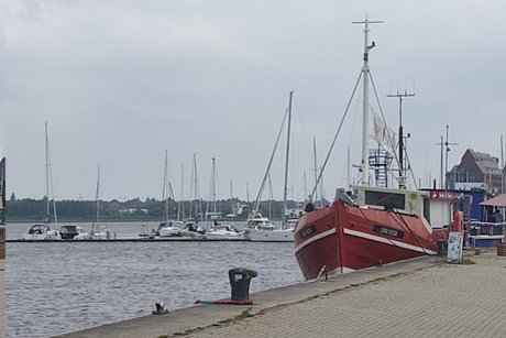 Abgebildet ist ein rotes Boot im Hafen