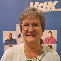 Eine lächelnde Frau mittleren Alters mit Brille und kurzen graumelierten Haaren