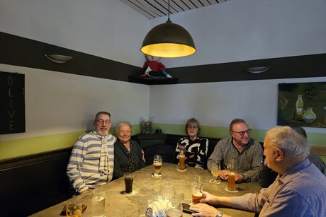 6 Personen sitzen am Tisch und haben ihre Getr&auml;nke vor sich