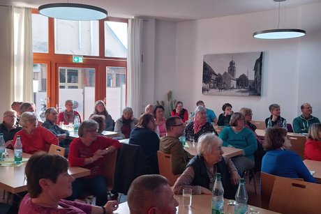 Mitglieder sitzen im Vortragsraum und hören einem Referenten zu.