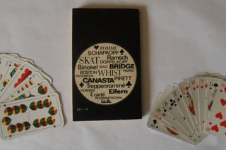 Bild zeigt ein Buch mit verschiedenen Kartenspielbezeichnungen und zwei Kartenspielblätter Skat und Schafkopf