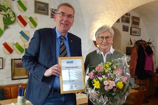 Abgebildet ist der VdK Kreisvorsitzende Bert Horn beim Überreichen eines Blumenstraußes sowie einer Dankurkunde an die scheidende Revisorin Brigita Hohenberger