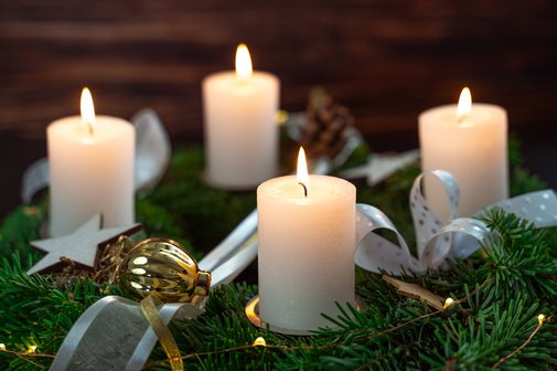 Festlicher Adventskranz auf Holz mit brennenden Kerzen zur Adventszeit.