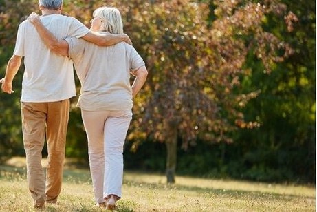 Ein etwas &auml;lteres Paar geht Arm in Arm auf einer Wiese.