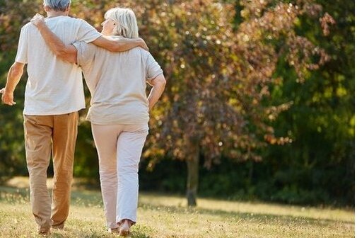 Ein etwas &auml;lteres Paar geht Arm in Arm auf einer Wiese.
