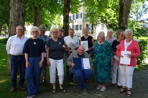 Eine Gruppe von Menschen stehen zusammen. Einige zeigen ihre Ehrenurkunden ins Bild.