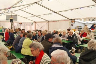 Gäste sitzen im Bierzelt und unterhalten sich.