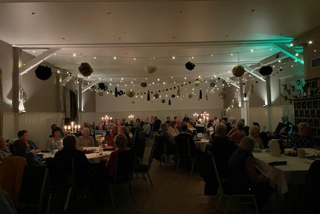 Saal mit G&auml;sten an Tischen im Kerzenschein