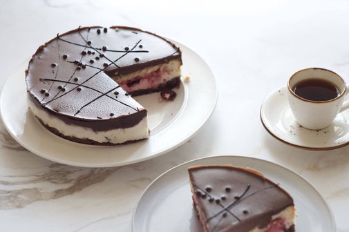 Kaffeekränzchen am 17.01.2026 In der Mitte steht ein angeschnittener Schoko-Sahne-Kuchen. Rechts daneben steht eine Tasse Kaffee. Davor steht ein Teller mit einem Stück Kuchen.
