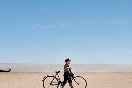 Plakatauschnitt des Films "Amrum" - ein Junge mit Fahrrad am Strand
