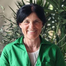 Frau Eisen, 1. Vorsitzende, l&auml;chelt freundlich, hat dunkle, lange, im Nacken zusammengebundene Haare und tr&auml;gt eine gr&uuml;ne Jacke.