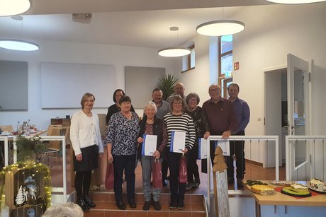 Mitglieder stehen mit ihrer Ehrungsurkunde zum Gruppenbild auf einer Treppe im Saal