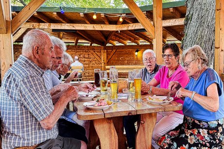 Biergartenbesuch 6 VdK-Mitglieder sitzen am Biertisch im Biergarten und unterhalten sich.