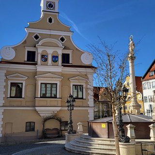 Auf dem Bild sieht man das Rathaus von Friedberg mit dem Brunnen auf dem Marienplatz