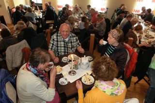 Auf dem Bild: VdK Reiseteilnehmer bei einer traditionellen Teezeremonie mit einem Stück „Ostfriesentorte“.