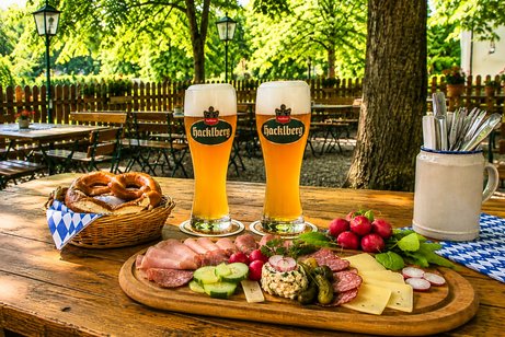 Brotzeit im Biergarten Brotzeit im Biergarten, auf dem Tisch stehen 2 Weißbiere und ein Brotzeitteller
