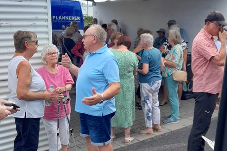 Ausfl&uuml;gler stehen an der Bushaltestelle und warten auf den Reisebus