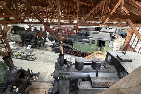 Ein Lokschuppen mit vielen alten Loks und Wagen