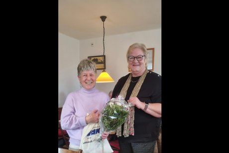 Auf dem Bild sind Burgi Mörtl-Körner, die eine VdK-Stofftasche und einen Blumenstrauß hält, den sie von der Vorsitzenden Helga Perschl *auch auf dem Bild) als Begrüßung im OV erhalten hat