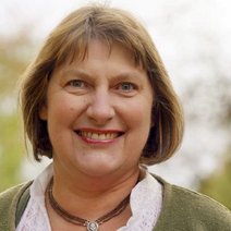 Beatrix Ertl l&auml;chelnd vor einer gr&uuml;nen Wiese mit B&auml;umen