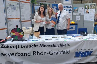 3 Personen an einem Infostand