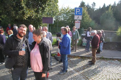 Man sieht die Mitfahrenden auf einem Parkplatz, die sich mit Brezen und Getränken stärken