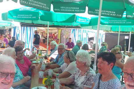 Gäste sitzen an Biertischen im Freien und feiern Kirchweih.