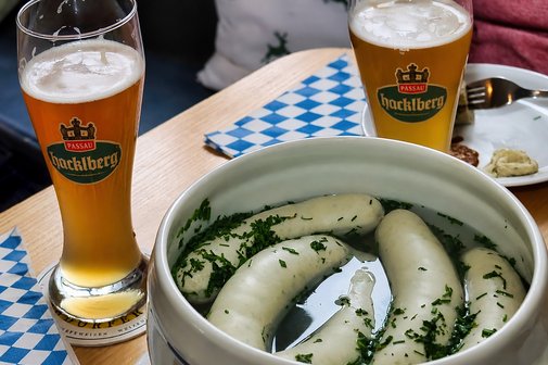 Leckere Wei&szlig;w&uuml;rste in der Terrine und ein Wei&szlig;bier stehen einladend auf dem Tisch.