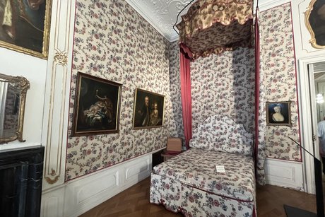 Das Schlafgemach. Ein Bett mit Baldachin und bespannte Wände im Schlafgemach.