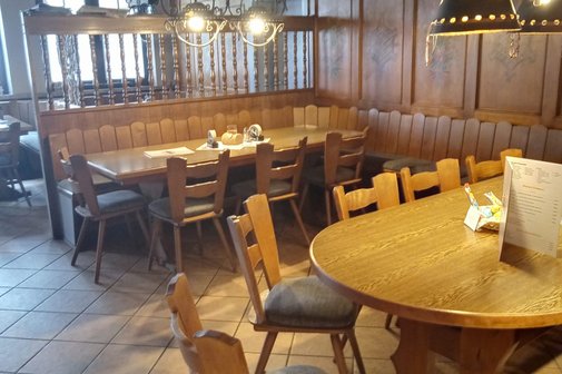 Blick in den vorderen mit zwei gro&szlig;en G&auml;stetische, Raumteiler als Gardrobenst&auml;nder und eingeschalteter Tischbeleuchtung, Speisekarte auf dem Tisch