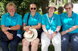 Vier Frauen die ein VdK-Poloshirt tragen, sitzend auf einer Bank